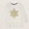 Young girl wearing a white long-sleeve top with a gold snowflake design on a plain background
