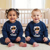 Two children wearing matching navy blue sweaters with astronaut graphics in a nursery.