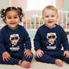 Two children wearing matching navy blue sweaters with astronaut graphics in a nursery.