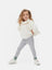Child wearing a white sweater and gray leggings on a white background