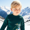 Young boy wearing a green sweatshirt with text and graphics against a mountainous background