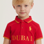 Child wearing a red polo shirt with 'Dubai' and a logo on a plain background