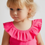 Child wearing a bright pink top with ruffled collar on a plain background