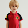 Child wearing a red and black polo shirt with a logo on a light gray background