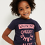 Child wearing a navy blue t-shirt with pink text on a white background