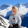 Child wearing a gray sweatshirt with construction vehicle icons against a snowy mountain background
