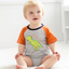 Baby wearing a gray and orange onesie with a dinosaur design on a white background