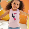 Young girl wearing a pink sleeveless shirt with a toucan design, standing in front of colorful balloons.