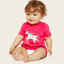Baby wearing a pink shirt with a unicorn design on a beige background