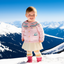 Child in a pink jacket standing on a snowy mountain with blue sky