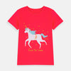 Baby wearing a pink shirt with a unicorn design on a beige background