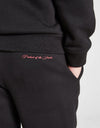 Person wearing a black 'Hood Rich' hoodie and pants with a red logo on a white background