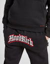 Person wearing a black 'Hood Rich' hoodie and pants with a red logo on a white background